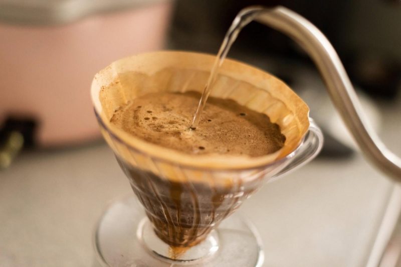 Hot water poured from a gooseneck kettle into a V60 dripper brewing specialty coffee