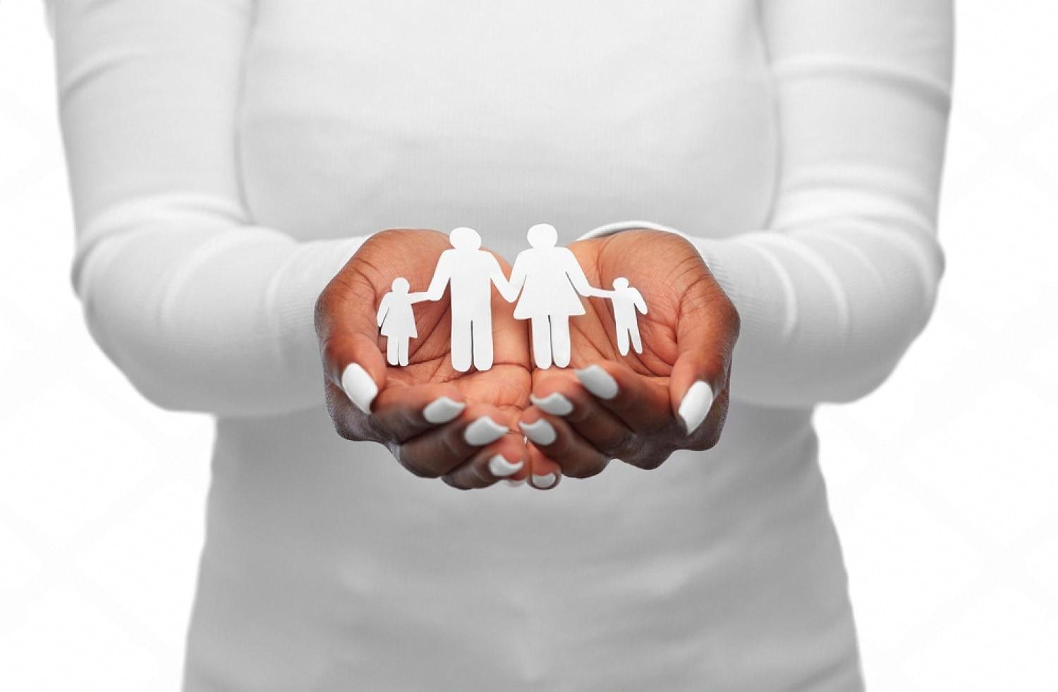 Cupped hands holding a paper cut-out of a family with two children symbolising family health insurance in the UAE
