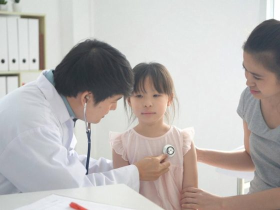 Pediatrician examining a young child with a stethoscope while the mother sits beside them during a Dubai clinic visit