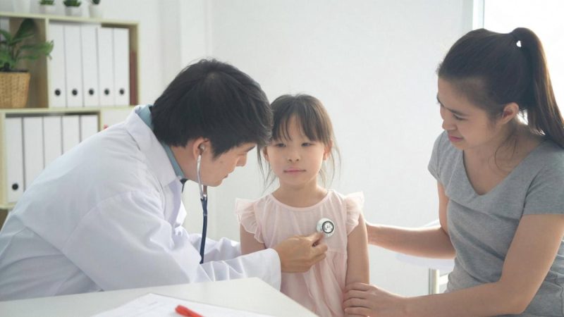 Pediatrician examining a young child with a stethoscope while the mother sits beside them during a Dubai clinic visit